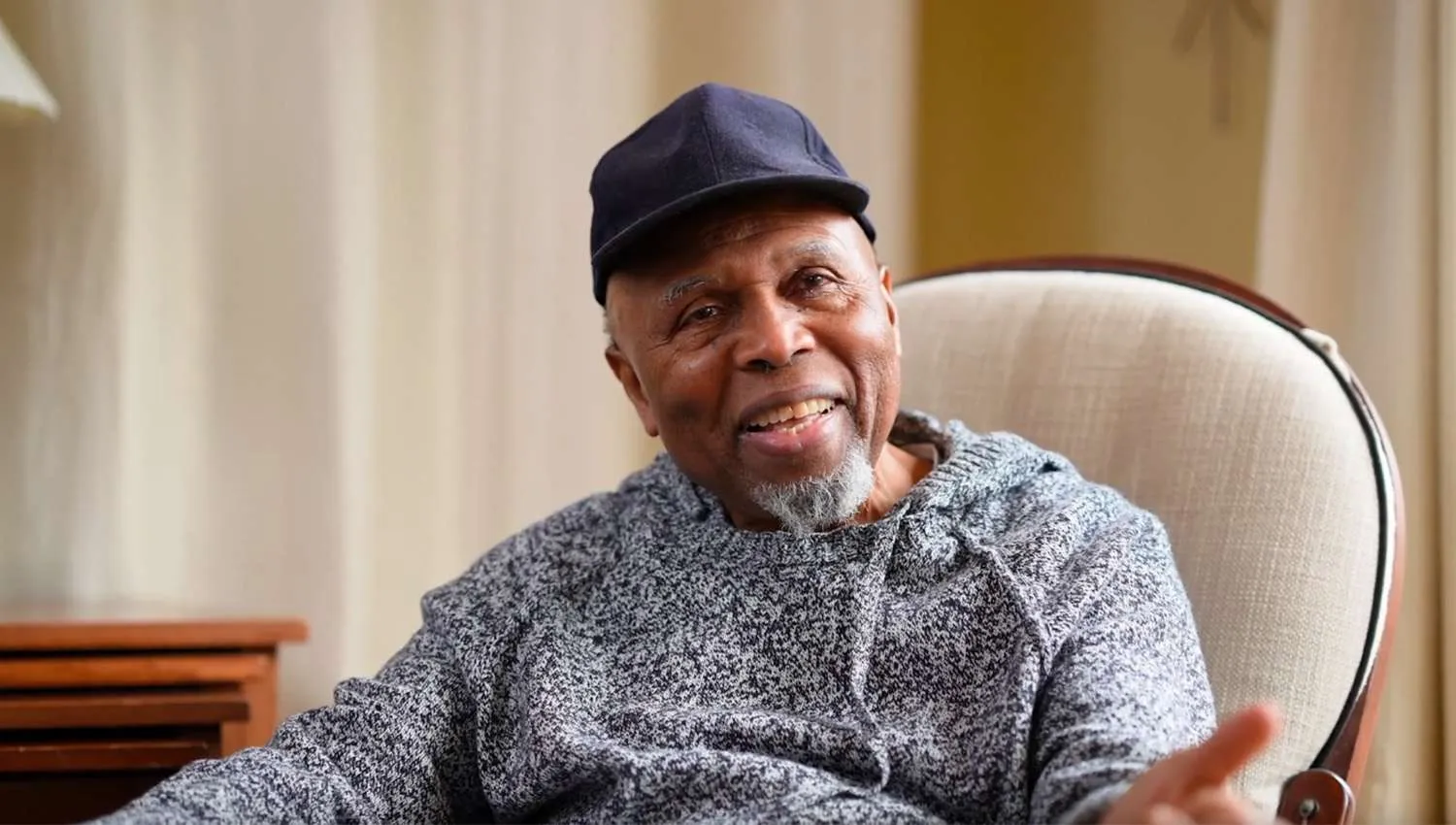 A man sitting in a chair with a hat on.